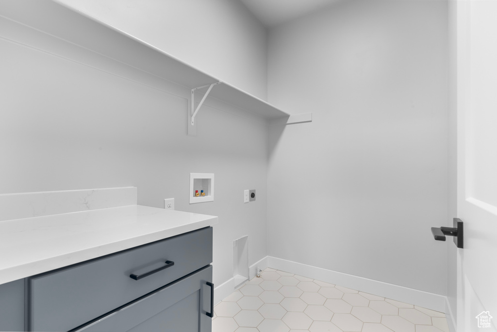Laundry room featuring washer hookup, electric dryer hookup, cabinet space, baseboards, and light tile patterned flooring