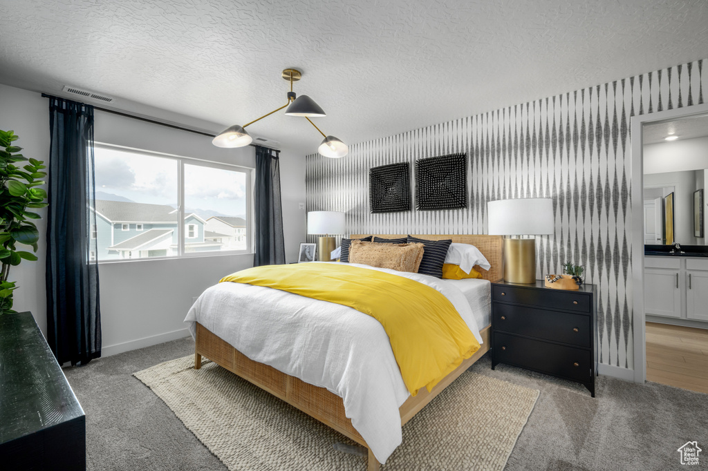 Bedroom with baseboards, light colored carpet, and a textured ceiling