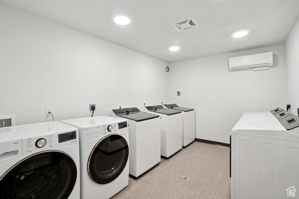 Shared laundry with washer and clothes dryer, a wall mounted air conditioner, light carpet, baseboards, and recessed lighting