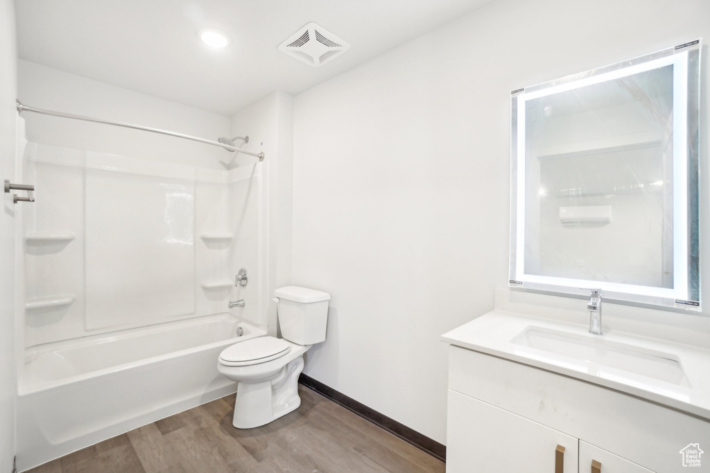 Bathroom featuring wood finished floors, toilet, vanity, bathing tub / shower combination, and baseboards