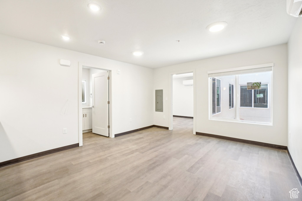 Unfurnished room with baseboards, light wood finished floors, recessed lighting, and a wall mounted AC