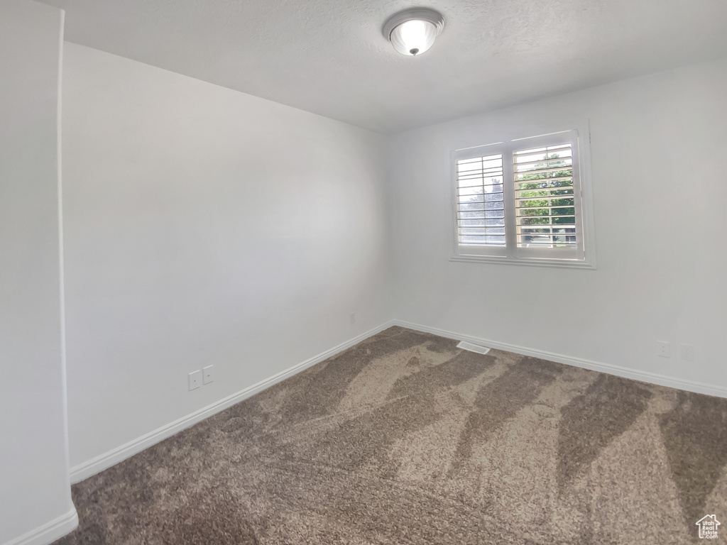 Empty room featuring carpet and baseboards