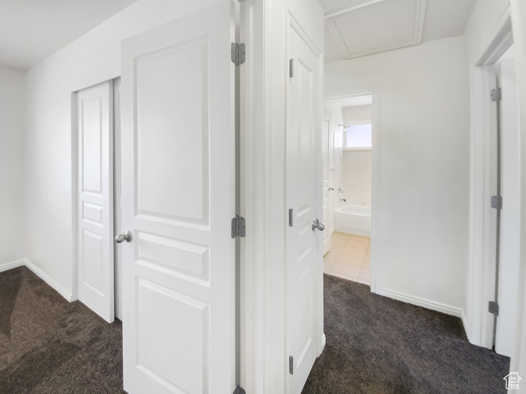 Corridor with dark carpet and baseboards