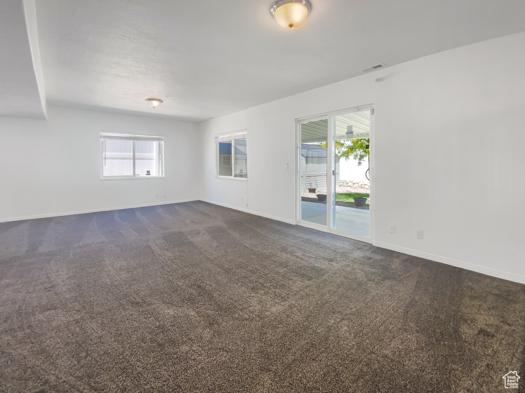 Unfurnished room with dark carpet and baseboards