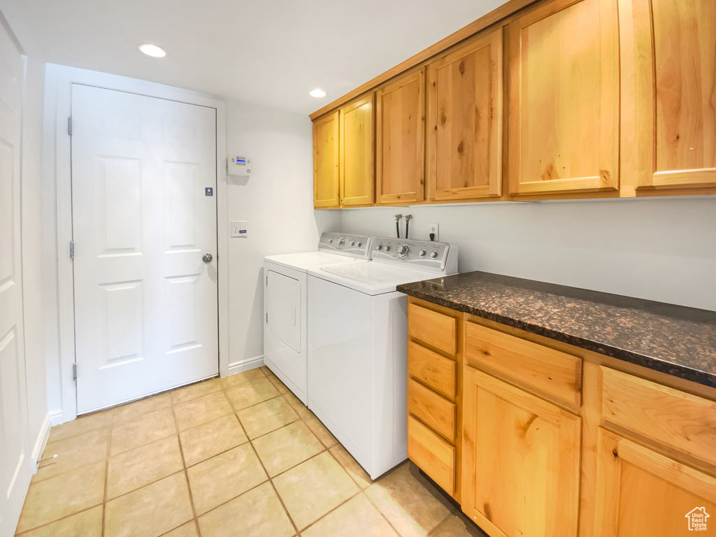Laundry area with cabinet space, separate washer and dryer, recessed lighting, light tile patterned floors, and baseboards