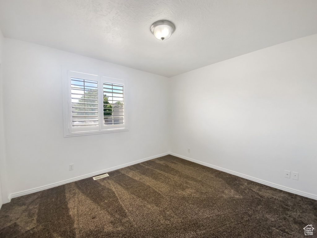 Empty room with dark carpet and baseboards