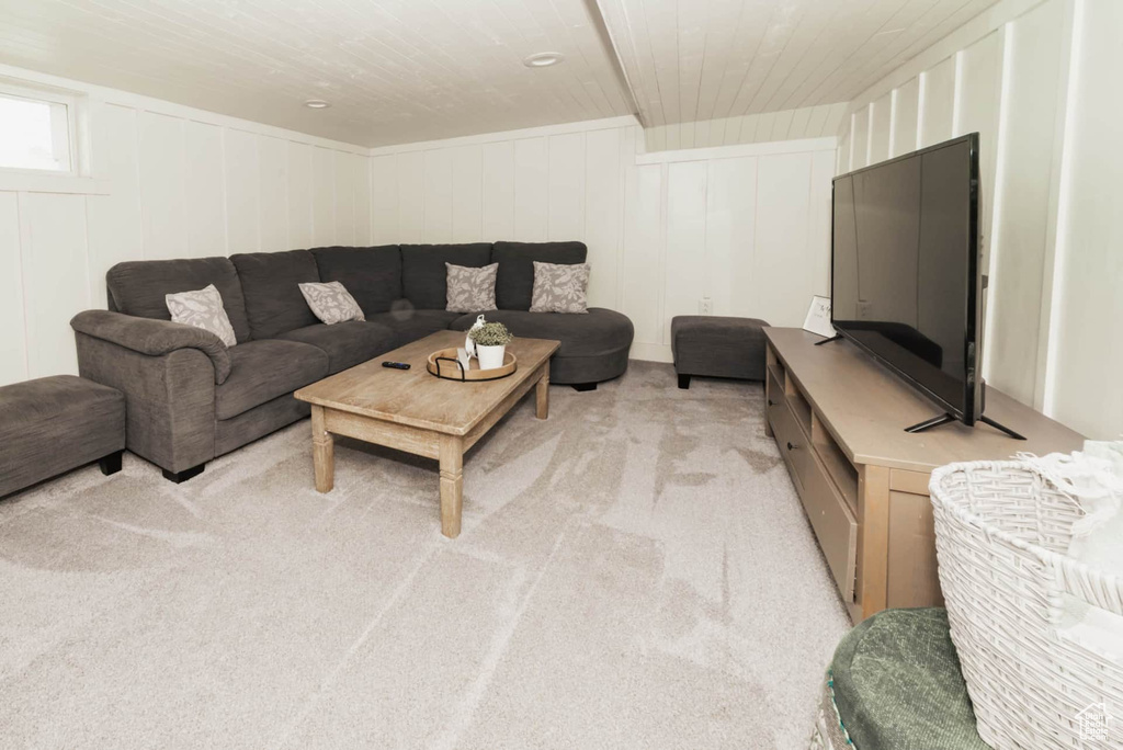 Living area featuring light colored carpet, wood ceiling, and a decorative wall