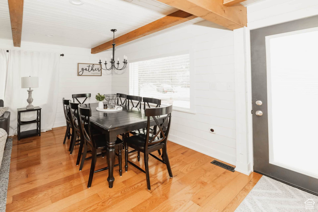 Dining space with beamed ceiling, light wood-style floors, and a chandelier