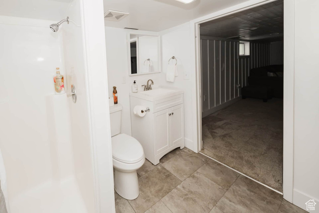 Bathroom featuring toilet, vanity, and a shower