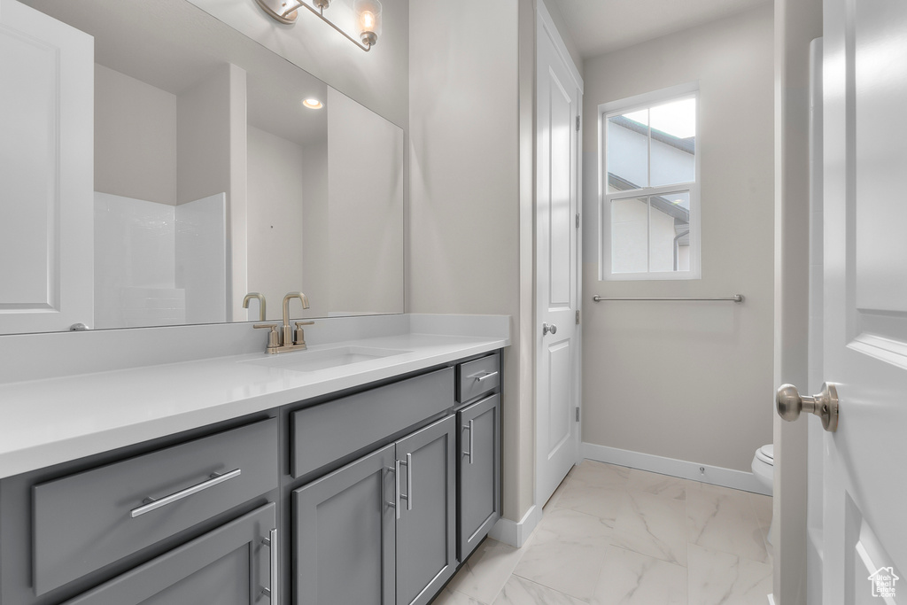 Bathroom featuring marble finish floors, vanity, toilet, baseboards, and recessed lighting