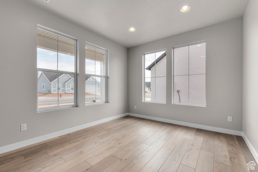 Unfurnished room with healthy amount of natural light, baseboards, recessed lighting, and light wood-style floors