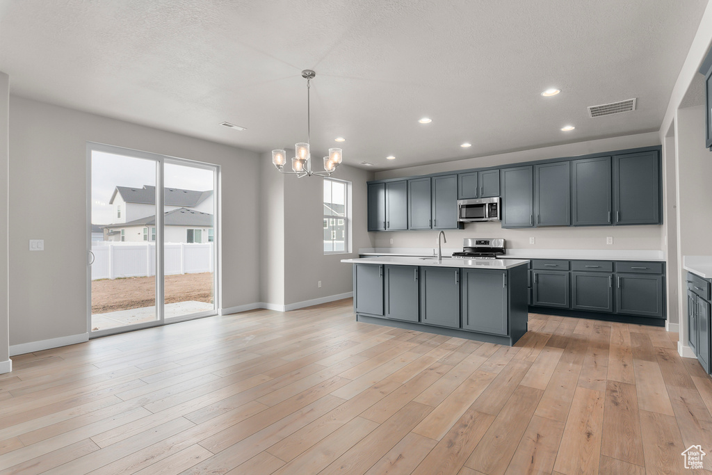 Kitchen featuring appliances with stainless steel finishes, a sink, light countertops, a chandelier, and recessed lighting