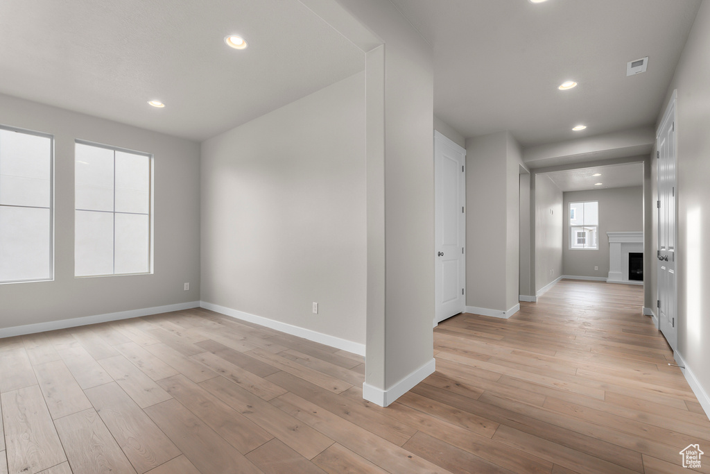 Unfurnished room featuring baseboards, light wood finished floors, recessed lighting, and a fireplace