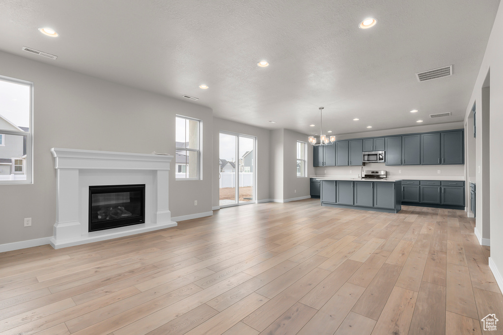 Kitchen featuring stainless steel appliances, light countertops, open floor plan, a chandelier, and baseboards