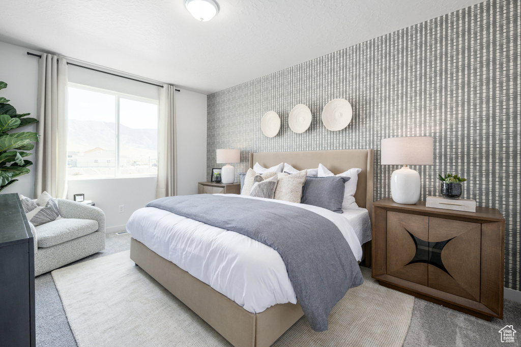 Bedroom with carpet floors, wallpapered walls, an accent wall, and baseboards