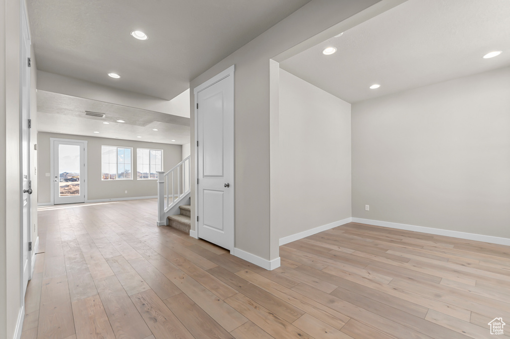Hall featuring baseboards, stairway, light wood-type flooring, and recessed lighting