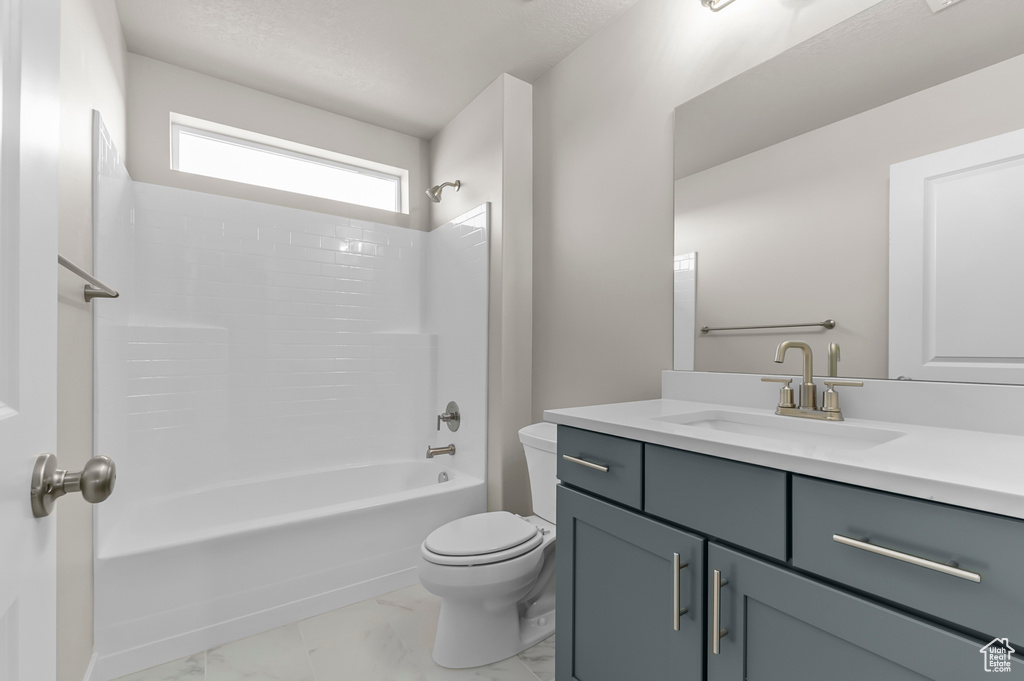 Full bath with toilet, vanity, marble finish flooring, and tub / shower combination