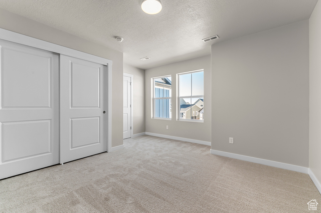 Unfurnished bedroom with carpet floors, baseboards, a textured ceiling, and a closet