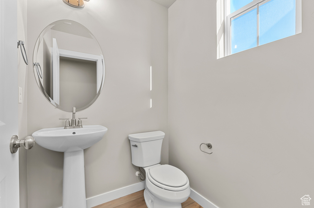 Bathroom featuring toilet, wood finished floors, and baseboards