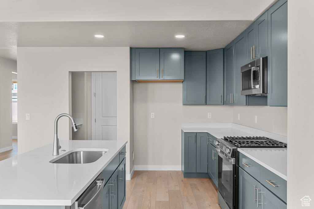 Kitchen featuring appliances with stainless steel finishes, a sink, light wood-style floors, light countertops, and recessed lighting