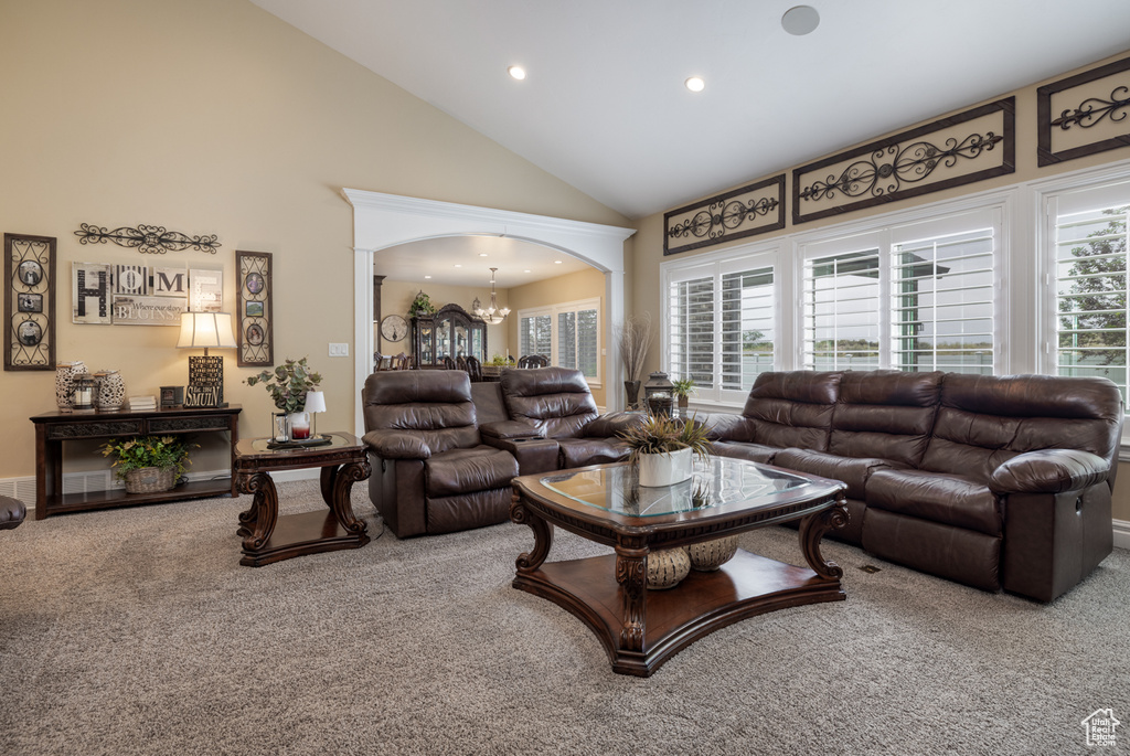 Living area with carpet, a chandelier, high vaulted ceiling, recessed lighting, and arched walkways