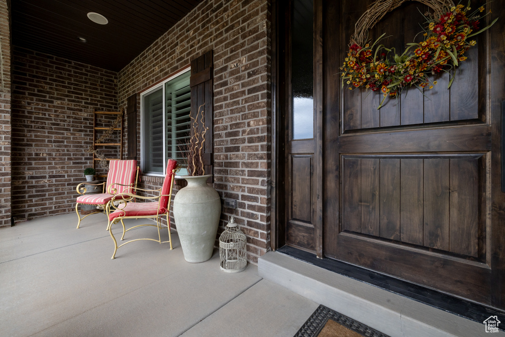 Doorway to property featuring brick siding and a porch