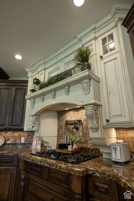 Kitchen with black gas stovetop, tasteful backsplash, dark brown cabinetry, dark stone counters, and recessed lighting
