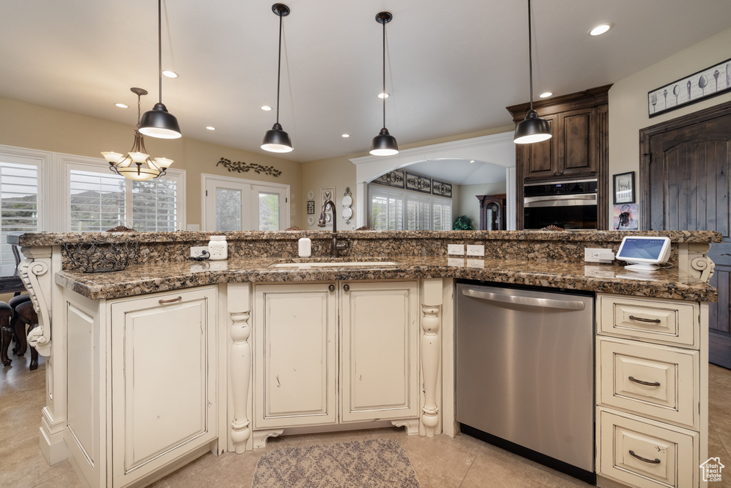 Kitchen featuring stainless steel appliances, a sink, cream cabinets, recessed lighting, and dark stone countertops