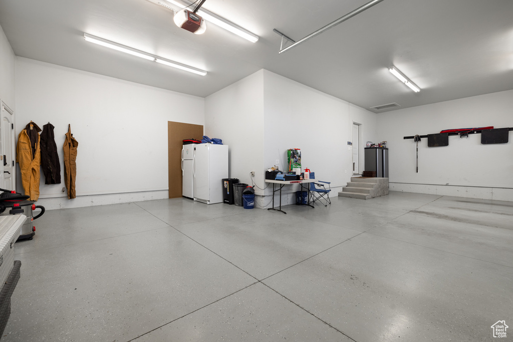 Garage with a garage door opener and freestanding refrigerator