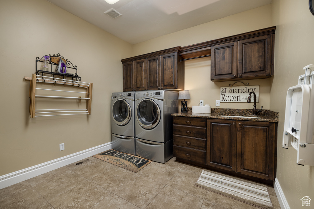 Laundry area with cabinet space, washing machine and dryer, baseboards, and light tile patterned flooring