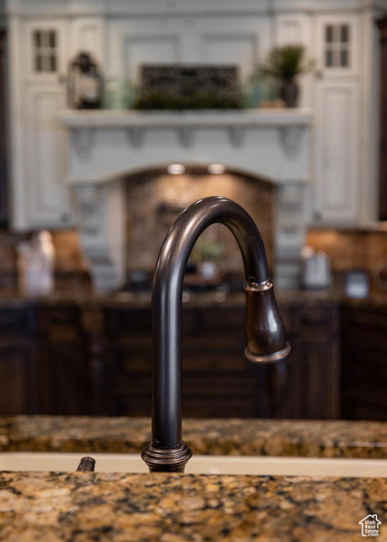 Detailed view of white cabinetry, glass insert cabinets, a sink, and dark countertops