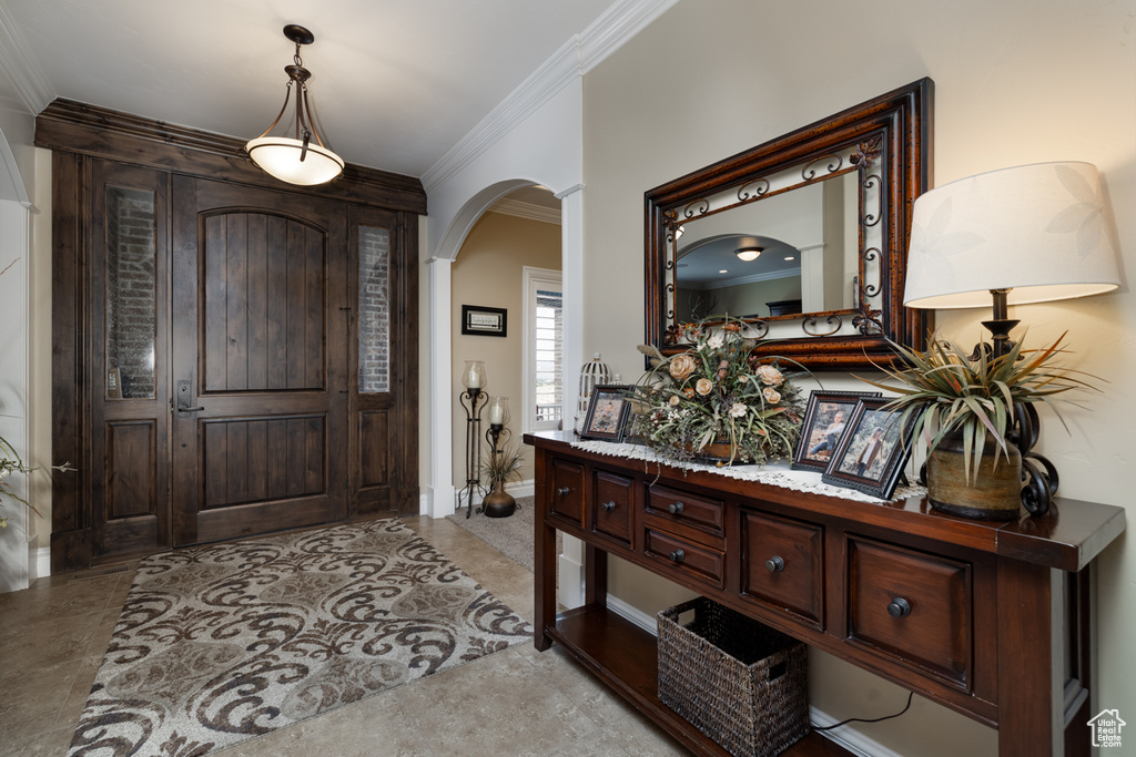 Foyer entrance featuring arched walkways, ornamental molding, and baseboards