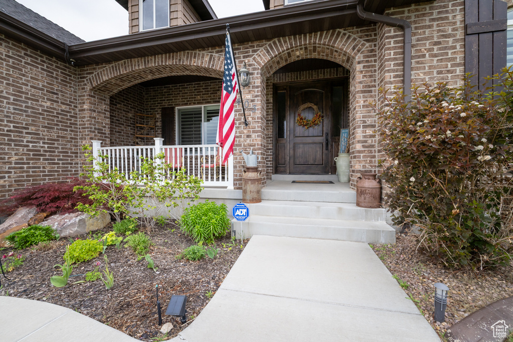 Doorway to property with brick siding and a porch