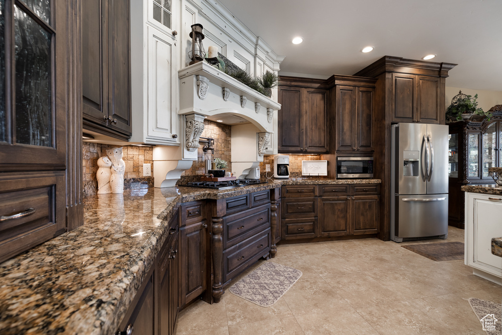 Kitchen featuring stainless steel appliances, tasteful backsplash, dark brown cabinetry, recessed lighting, and dark stone countertops