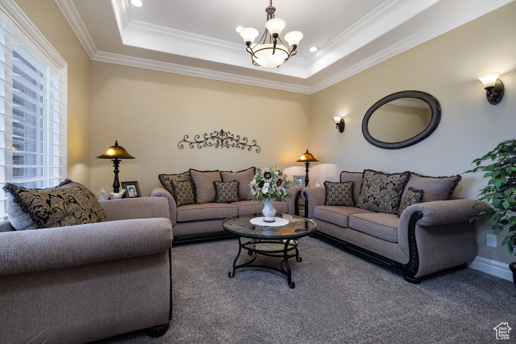 Carpeted living room featuring a chandelier, crown molding, and a tray ceiling