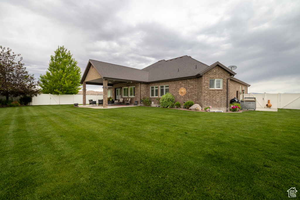 Back of house with a patio, brick siding, a shingled roof, and a gate