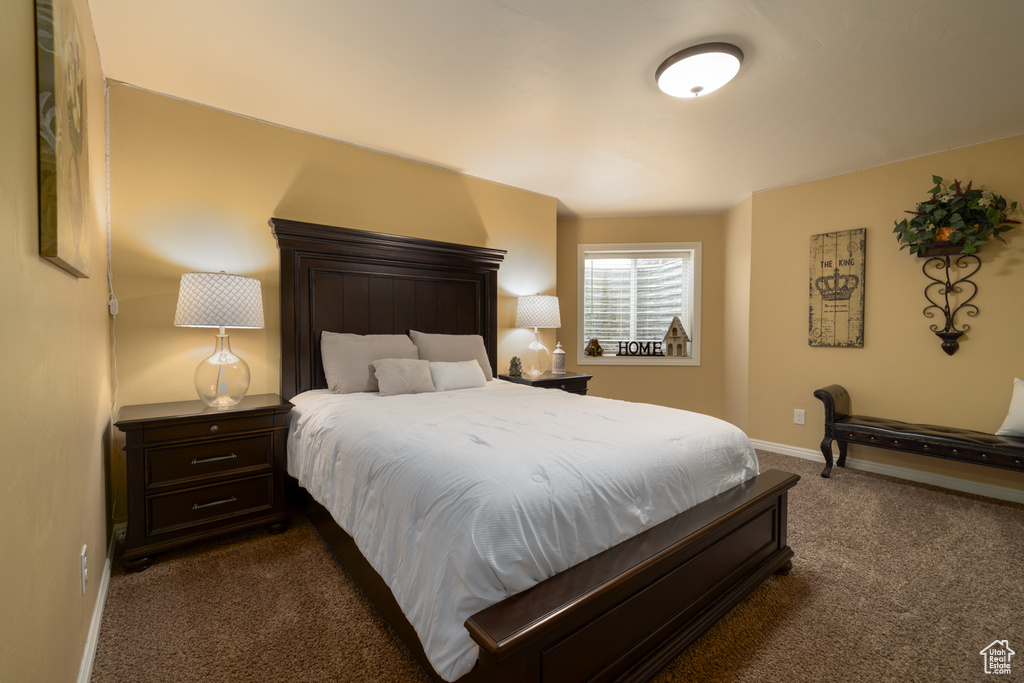 Bedroom with dark colored carpet and baseboards