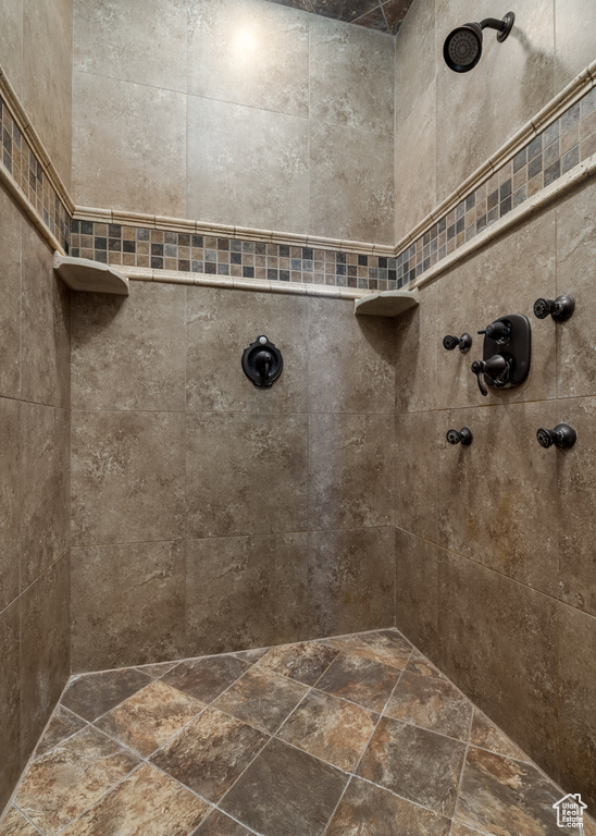 Full bath with a tile shower and stone finish floors