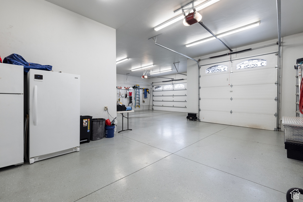 Garage with freestanding refrigerator and a garage door opener