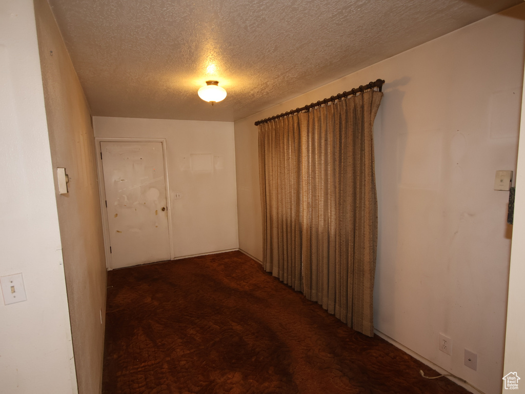 Corridor with a textured ceiling and dark carpet