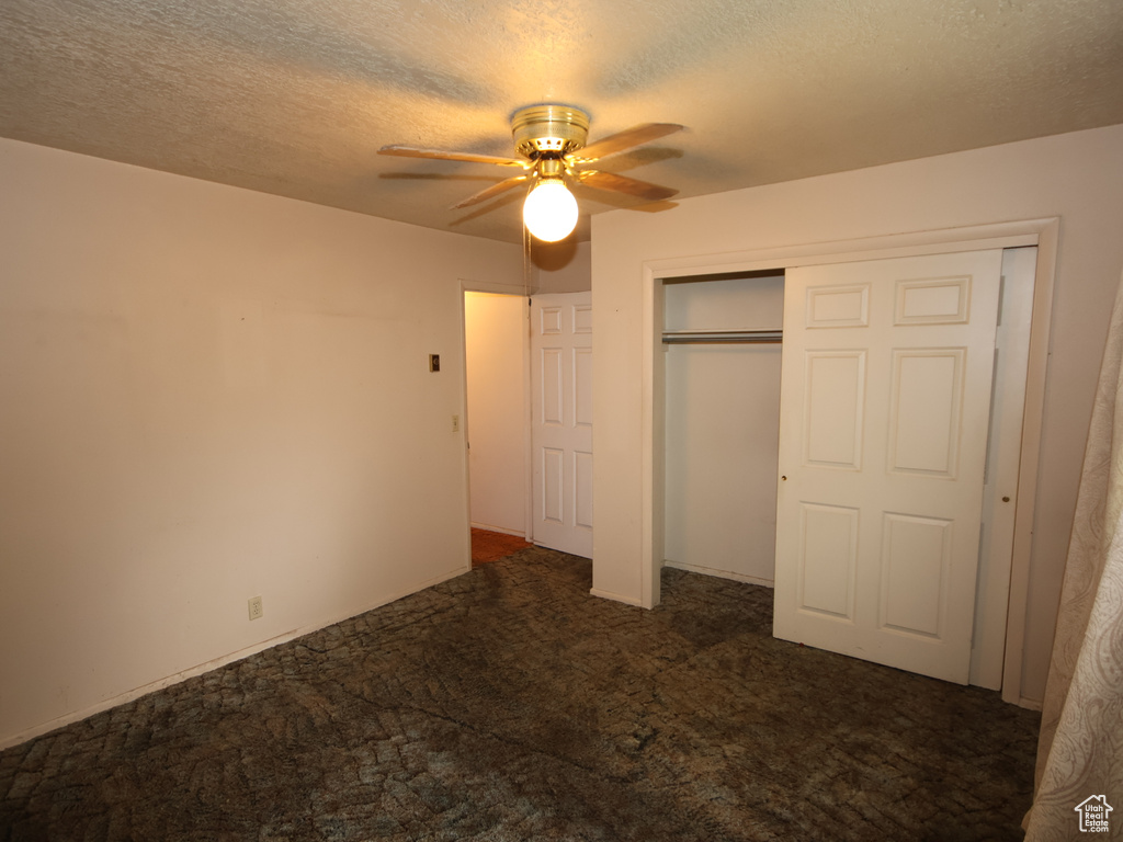 Unfurnished bedroom featuring carpet, a textured ceiling, a closet, and a ceiling fan
