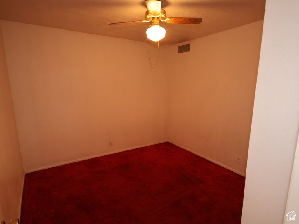 Unfurnished room with a ceiling fan, dark colored carpet, and baseboards