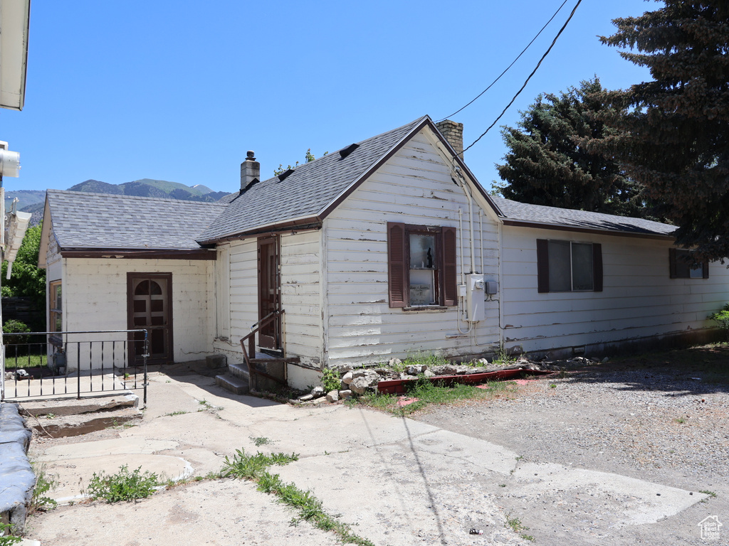 View of front of home with a chimney, a shingled roof, and a mountain view