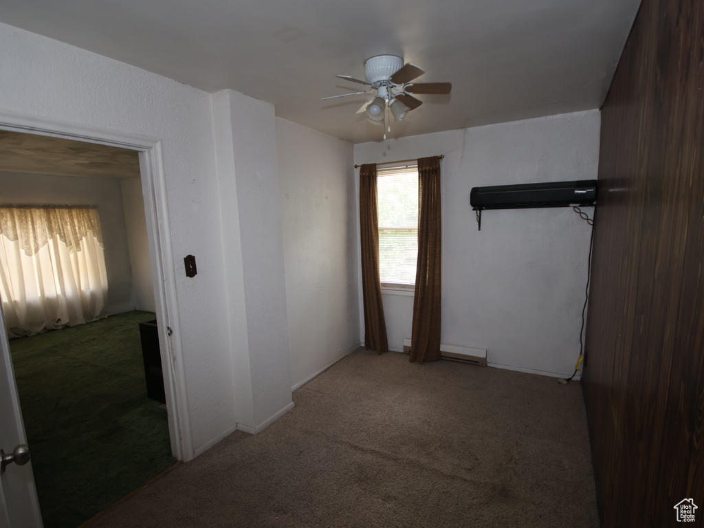 Spare room featuring a ceiling fan, carpet, baseboard heating, and baseboards