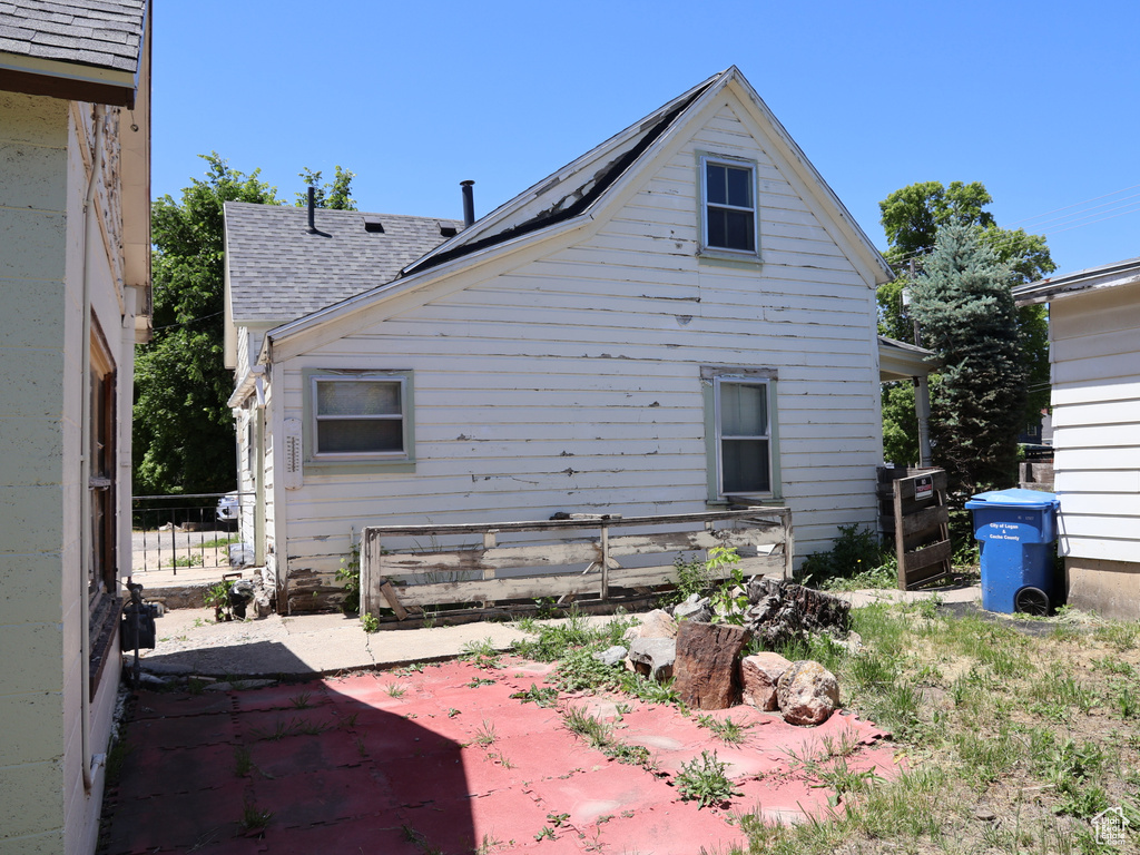 Rear view of house with a patio area and a shingled roof