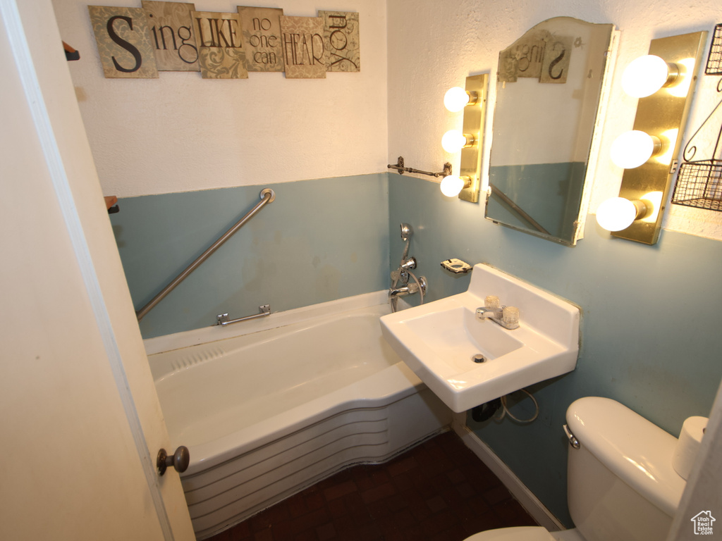 Bathroom featuring a garden tub, toilet, and a sink