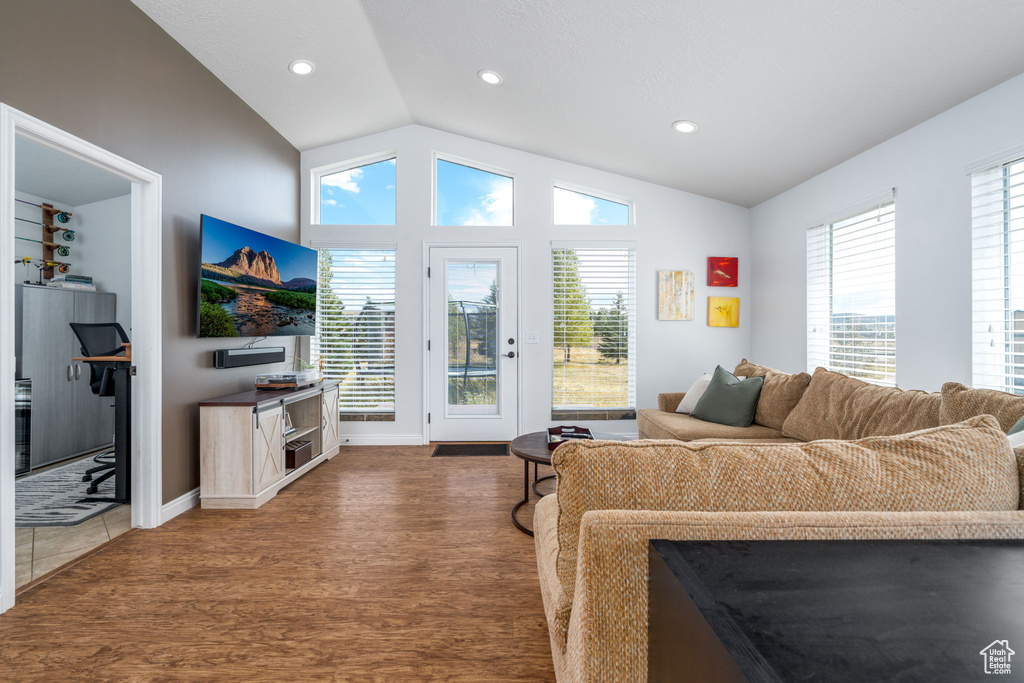 Living room with lofted ceiling, wood finished floors, plenty of natural light, recessed lighting, and baseboards