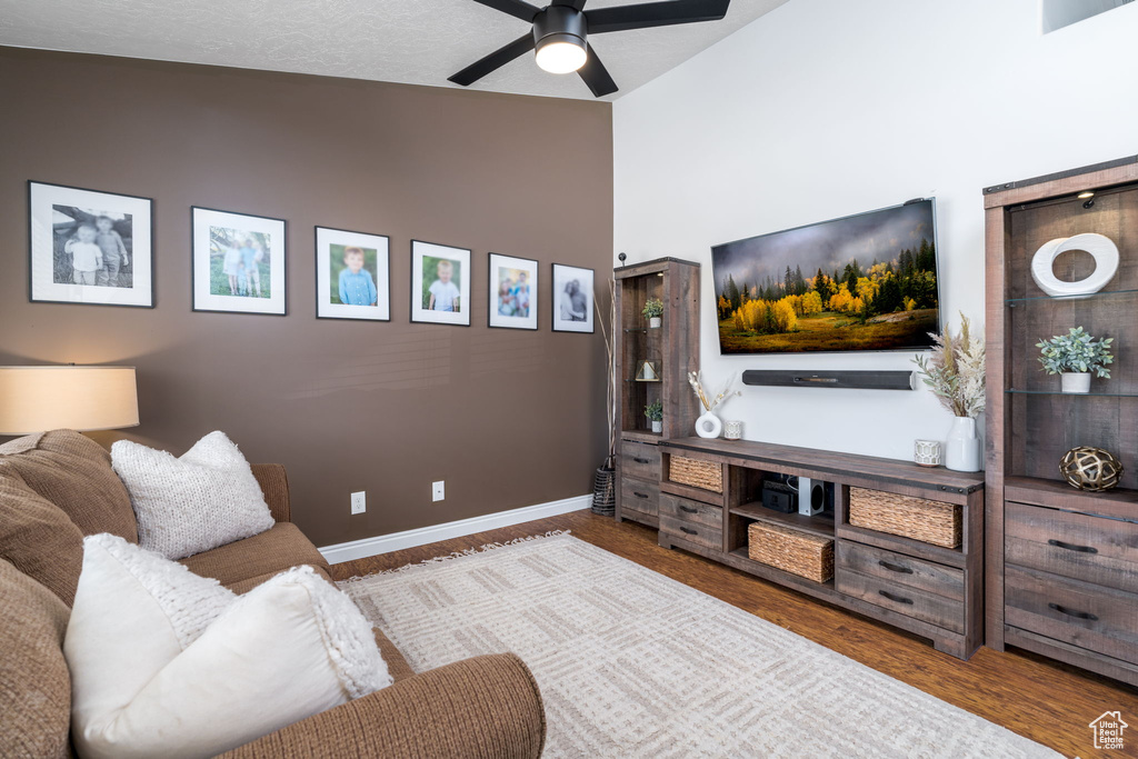 Living room with lofted ceiling, a ceiling fan, baseboards, and wood finished floors
