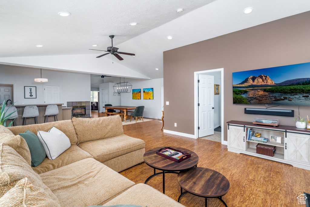 Living area featuring wood finished floors, lofted ceiling, ceiling fan, recessed lighting, and baseboards