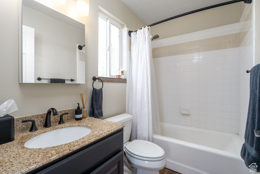 Bathroom with toilet, shower / bath combo, and vanity